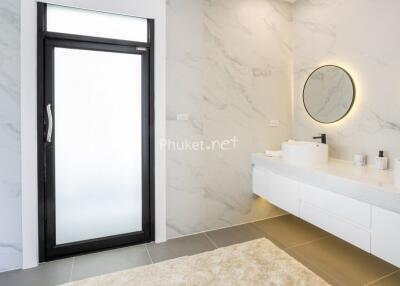 Modern bathroom with large mirrors, double sinks, and marble walls