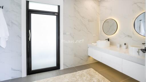 Modern bathroom with large mirrors, double sinks, and marble walls