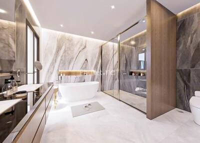 Modern bathroom with marble walls, bathtub, glass shower, and toilet