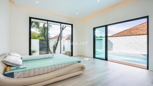 Well-lit modern bedroom with large windows and pool view