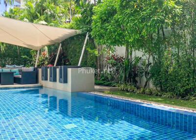 Outdoor pool area with lounge seating and lush greenery