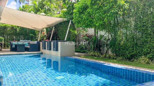 Outdoor pool area with lounge seating and lush greenery