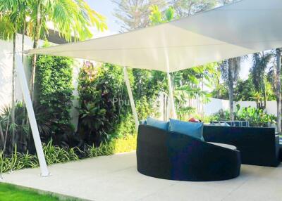 Covered outdoor patio with seating and lush greenery