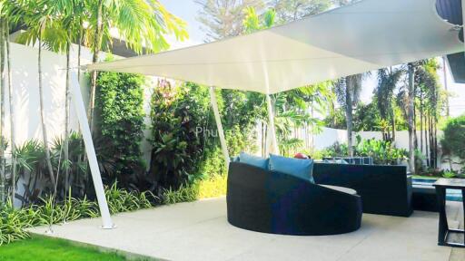 Covered outdoor patio with seating and lush greenery