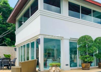 Exterior view of a modern two-story house with large glass windows and a patio