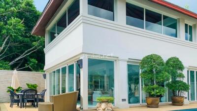 Exterior view of a modern two-story house with large glass windows and a patio