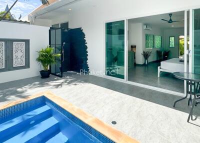 Outdoor view of a modern property with a pool and sliding doors leading to an indoor area