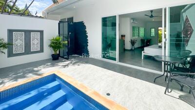 Outdoor view of a modern property with a pool and sliding doors leading to an indoor area