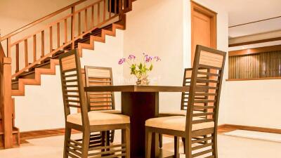 Dining area with table and four chairs next to a wooden staircase