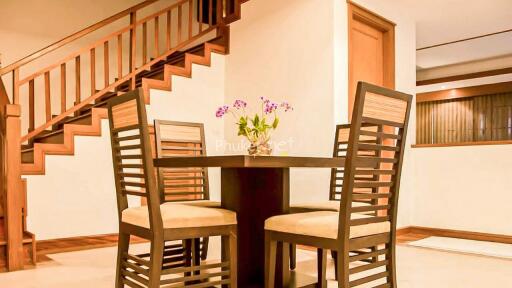 Dining area with table and four chairs next to a wooden staircase