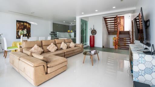 Modern living room with comfortable seating, stairway, and open kitchen view