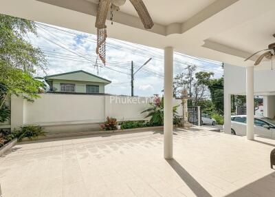 Spacious outdoor patio with ceiling fans, car parking, and garden area