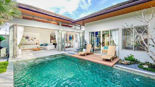 Outdoor pool area with lounge chairs and view into modern living room