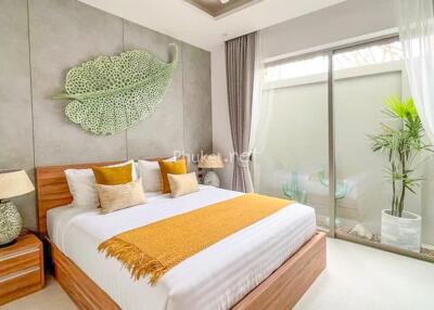 Modern bedroom with large bed, decorative leaf wall piece, and sliding glass door to patio