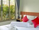 Comfortable bedroom with large window and red accent pillows