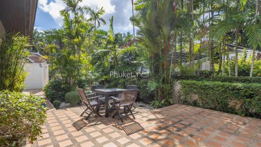 Outdoor patio area with table and chairs surrounded by tropical plants