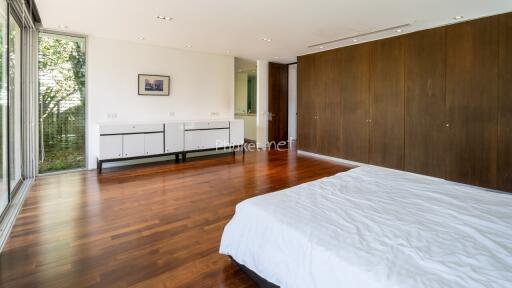 Spacious bedroom with wooden flooring and large windows