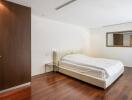 Bedroom with a white bed, wooden wardrobe, and a wall mirror