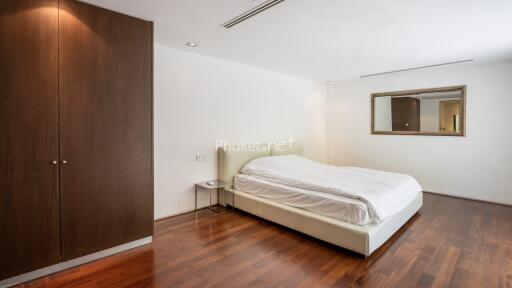 Bedroom with a white bed, wooden wardrobe, and a wall mirror