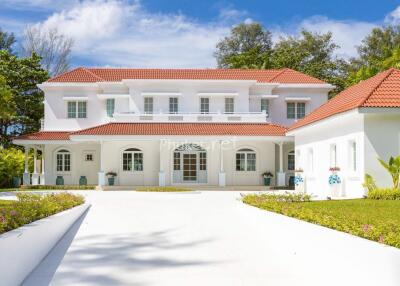 Beautiful large white two-story house with red roof and lush green surroundings