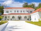 Beautiful large white two-story house with red roof and lush green surroundings