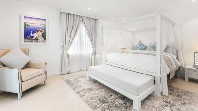 Spacious bedroom with a cozy four-poster bed, armchair, and elegant decor