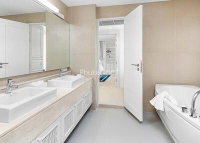 Modern bathroom with dual sinks, large mirror, and a bathtub