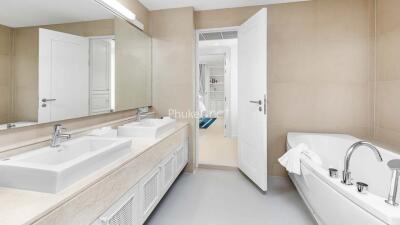 Modern bathroom with dual sinks, large mirror, and a bathtub