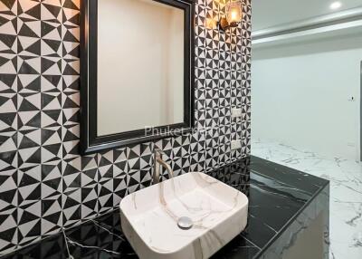 Modern bathroom with geometric black and white tiles, marble counter, and large mirror