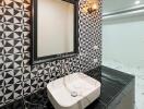 Modern bathroom with geometric black and white tiles, marble counter, and large mirror