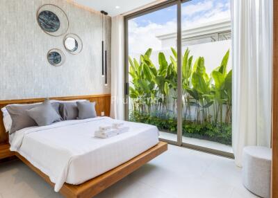 Modern bedroom with large window and plants outside