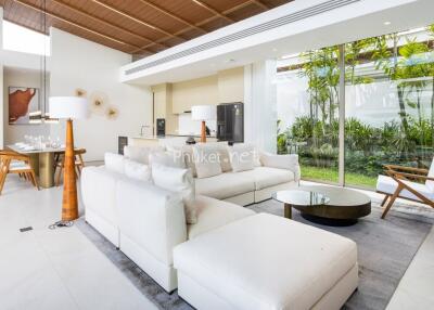 Modern living room with white sofa, dining area, and large windows