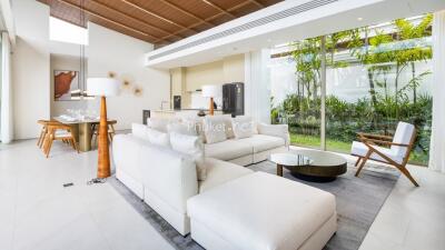 Modern living room with white sofa, dining area, and large windows