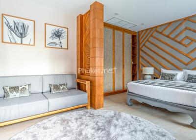 Spacious and modern bedroom with stylish wooden accents, a sofa, and large bed