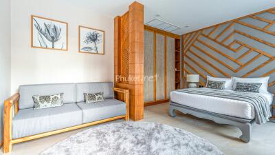 Spacious and modern bedroom with stylish wooden accents, a sofa, and large bed