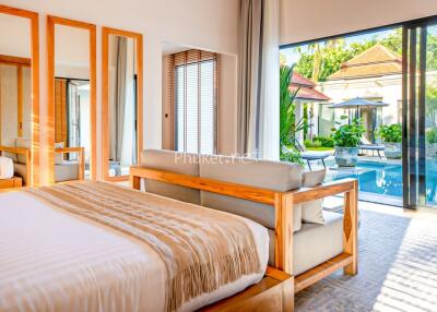 Bright bedroom with wooden furniture and a large window overlooking a pool