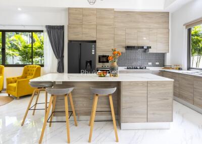 Modern kitchen with island, bar stools, yellow armchairs, and large windows