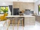 Modern kitchen with island, bar stools, yellow armchairs, and large windows