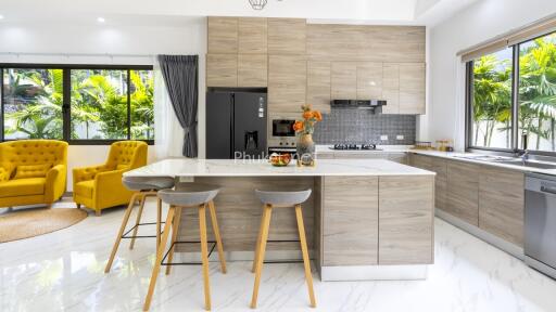 Modern kitchen with island, bar stools, yellow armchairs, and large windows