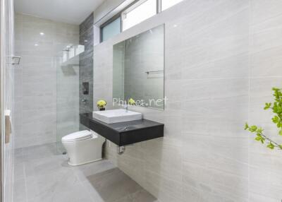 Modern bathroom with vanity, large mirror, toilet, and walk-in shower