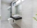 Modern bathroom with vanity, large mirror, toilet, and walk-in shower