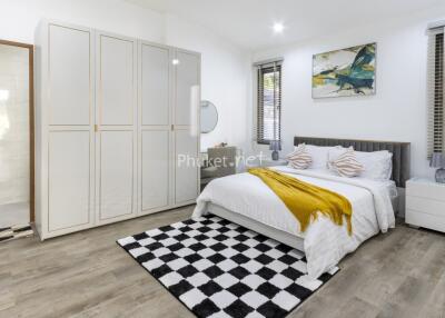 Modern bedroom with a large bed, checkered rug, and wardrobe