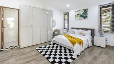 Modern bedroom with a large bed, checkered rug, and wardrobe