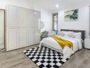 Modern bedroom with a large bed, checkered rug, and wardrobe