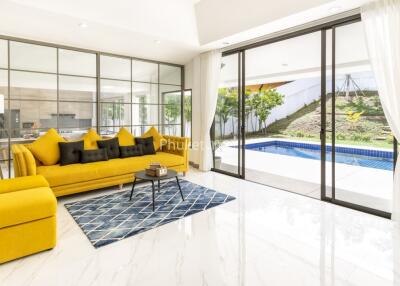 Spacious and bright living room with large glass doors leading to a pool and outdoor area