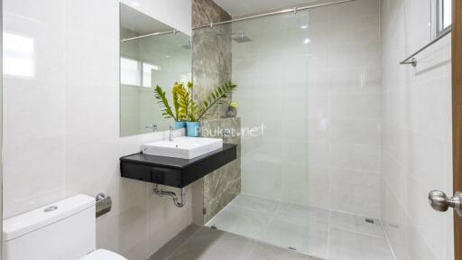 Modern bathroom with a glass shower, large mirror, and a sink with a vase of plants
