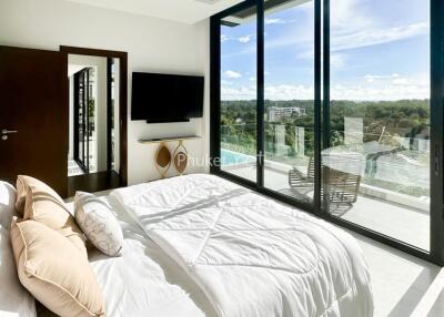 Modern bedroom with large glass door opening to a scenic balcony view