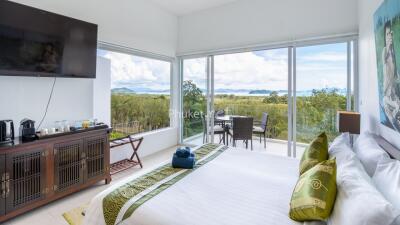 Bright bedroom with large windows showing a scenic outdoor view