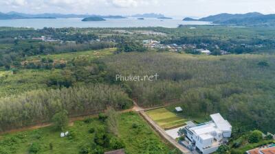Aerial view of a property near a coastline with lush greenery and hills in the distance