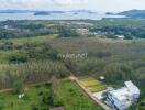 Aerial view of a property near a coastline with lush greenery and hills in the distance